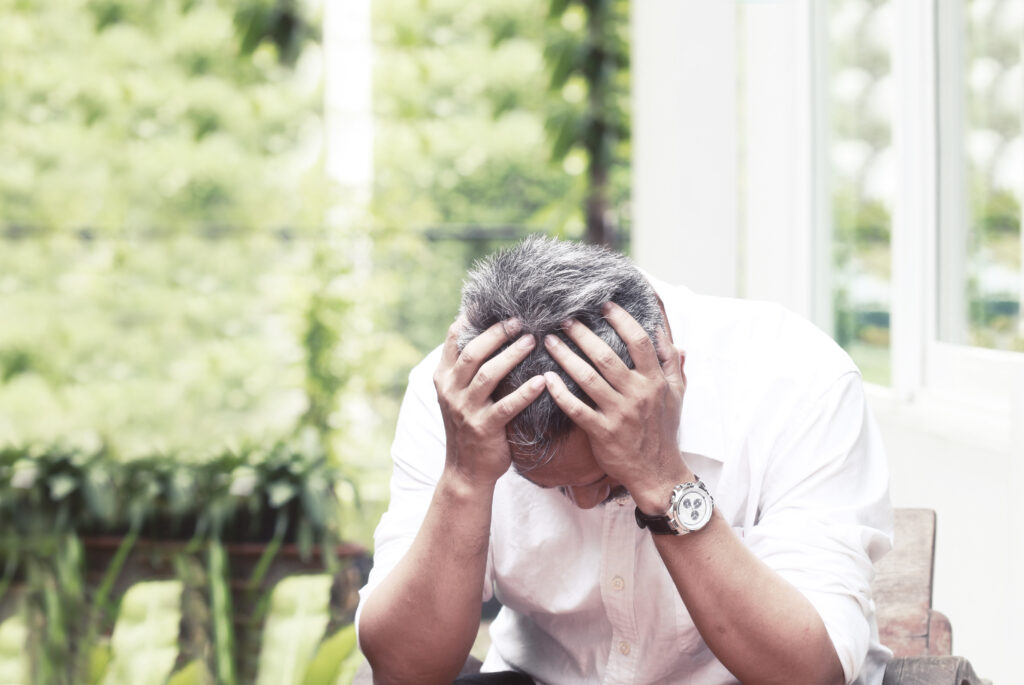 Muž ve stresu sedí a drží se za hlavu