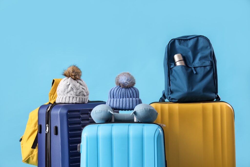 Kufry různých barev a velikostí na modrém pozadí