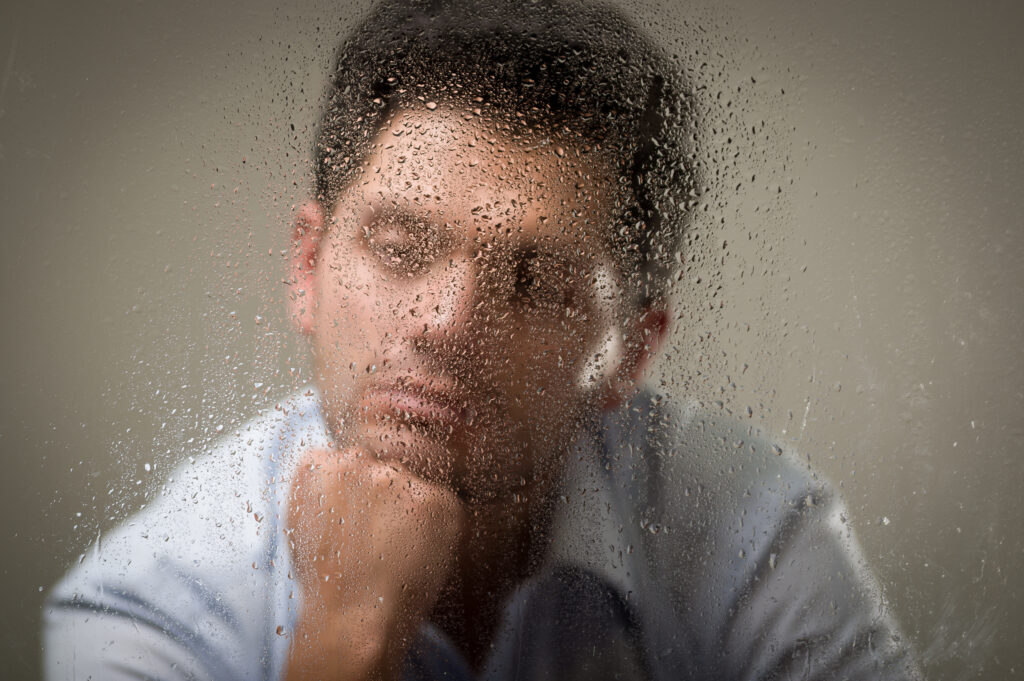 Smutný muže sedí za zamlženým sklem