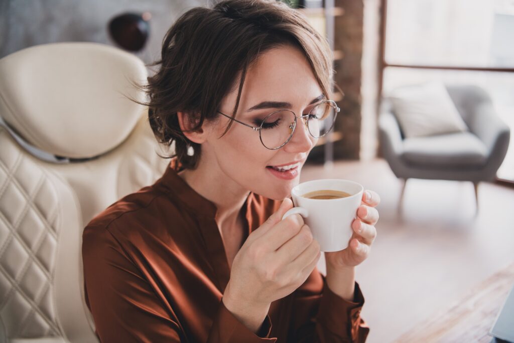 Žena sedí a drží v ruce hrnek kávy