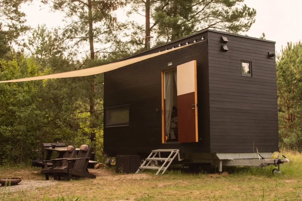 Tiny house, před n&iacute;mž jsou židle a stůl.