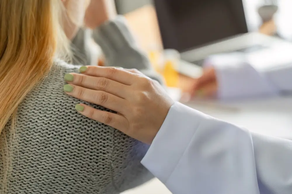 Žena dává ruku na rameno dívky na znamení podpory.