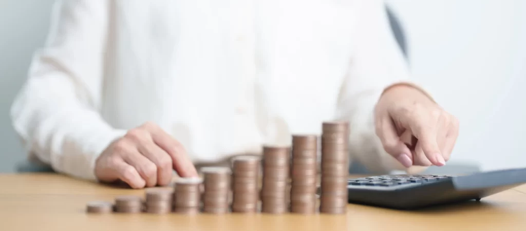 Muž počítající peníze na kalkulačce. 