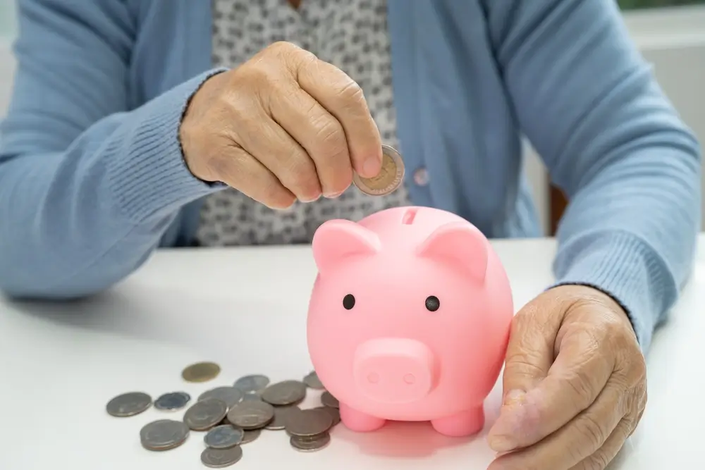 Žena dává peníze do prasátka. 