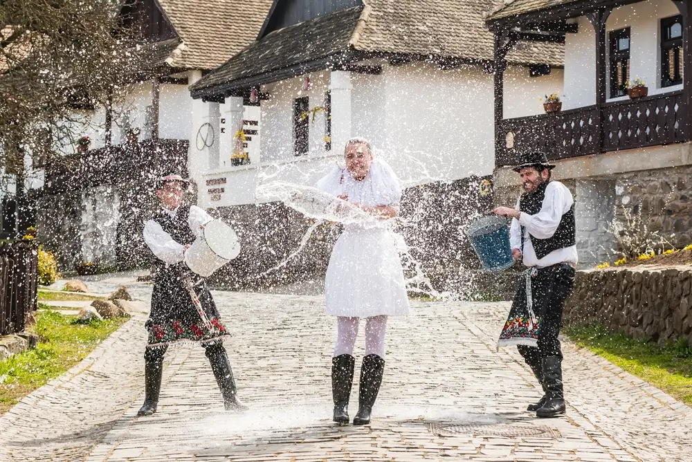 Koledníci polévají slečnu vodou.