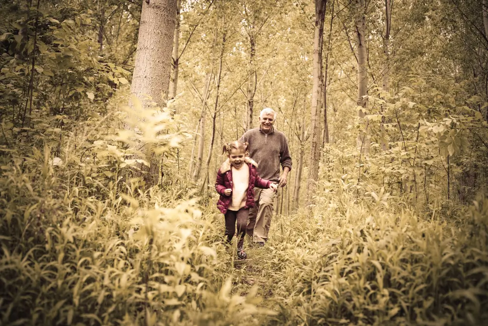 Dědeček běž&iacute; se svou vnučkou skrze les. 