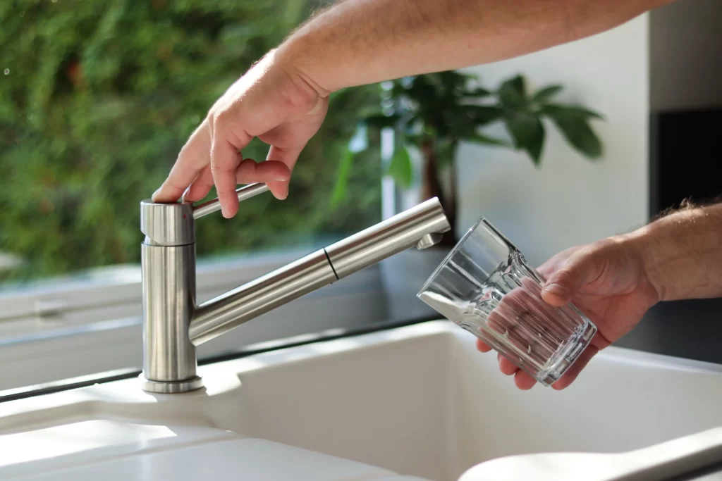 Ruka, kter&aacute; napou&scaron;t&iacute; sklenici vody z kohoutku.