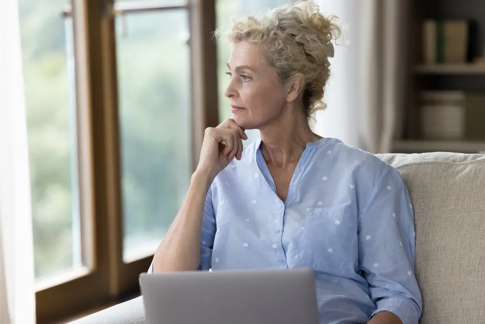 Žena přem&yacute;&scaron;l&iacute; a hled&iacute; z okna. 