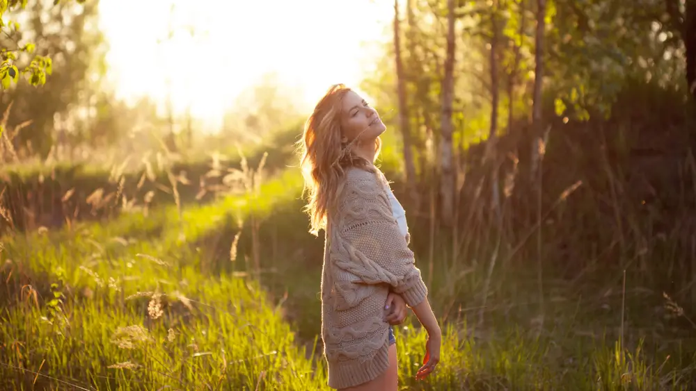Žena se nastavuje slunečním paprskům. 