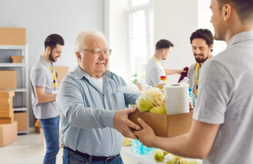 Starší člověk, který si přebírá krabici s jídlem.