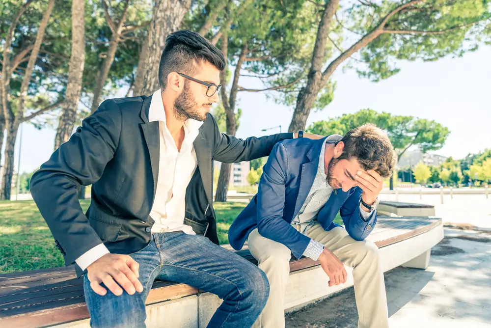 Muž plácá svého kamaráda po zádech na znamení podpory.