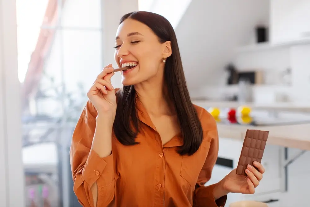 Žena jí čokoládu a směje se.