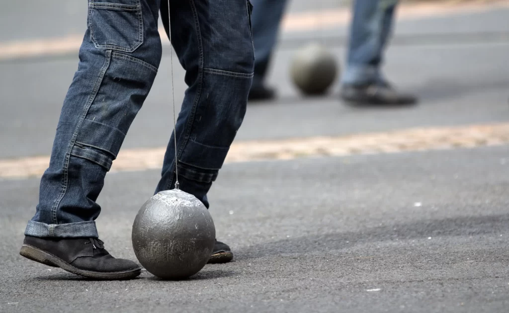 Nohy muže s koulí u nohy.