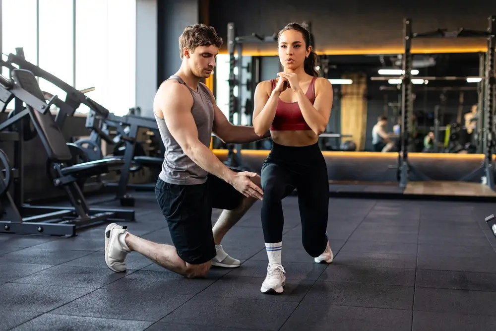 Žena je na tréninku v posilovně s trenérem.