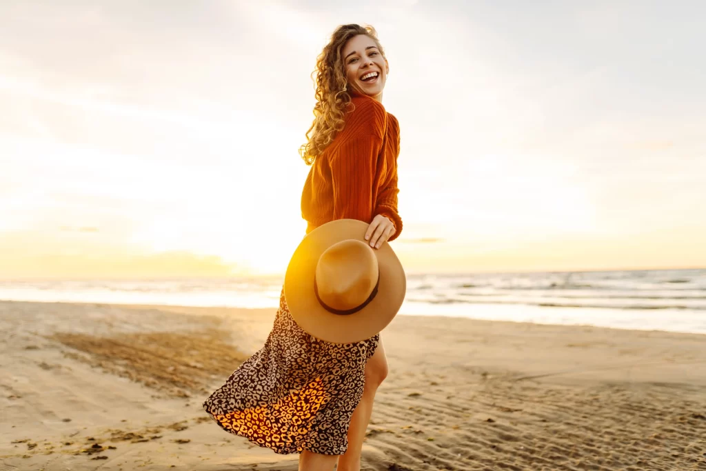 Žena s kloboukem na pláži.