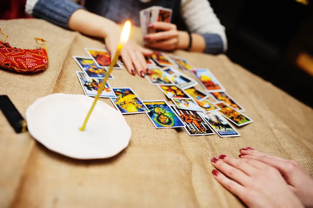 Tarotov&eacute; karty na stole, u něhož sed&iacute; ženy. 
