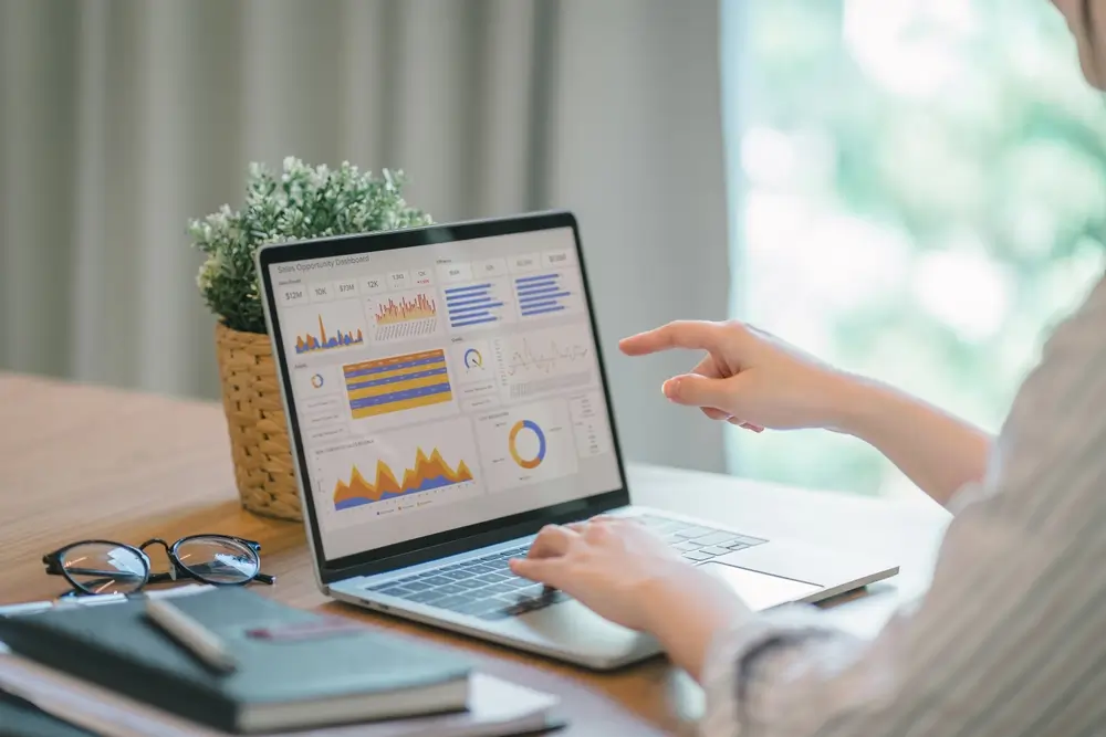 Žena pracuje na notebooku s grafy. 