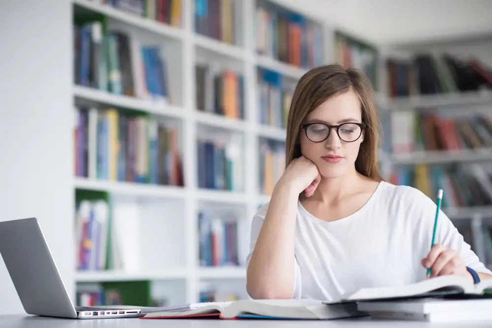 Žena se uč&iacute; v knihovně. 