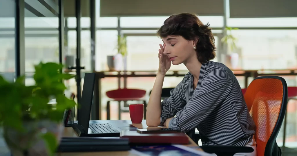 Žena sedící u stolu a telefonuje.