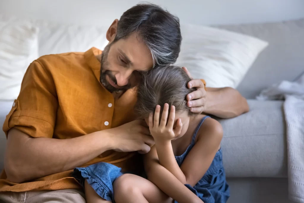 Muž utě&scaron;uj&iacute;c&iacute; plač&iacute;c&iacute; dceru.