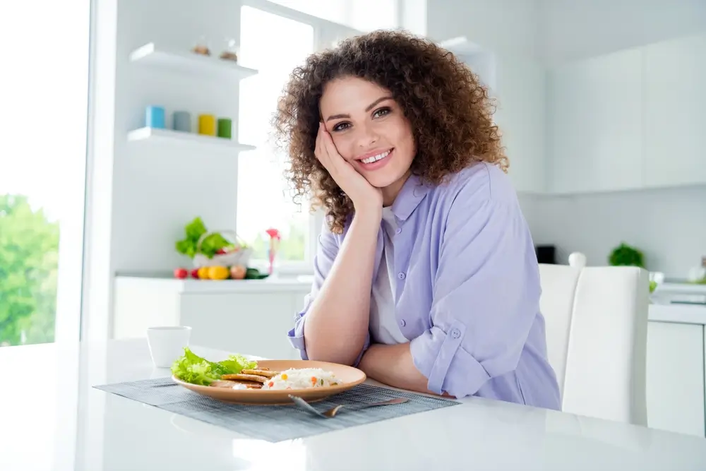 Žena sedí u talíře s rýží.