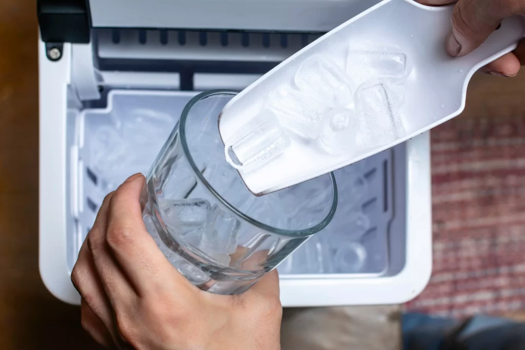 Ruka člověka dávající led do skleničky.