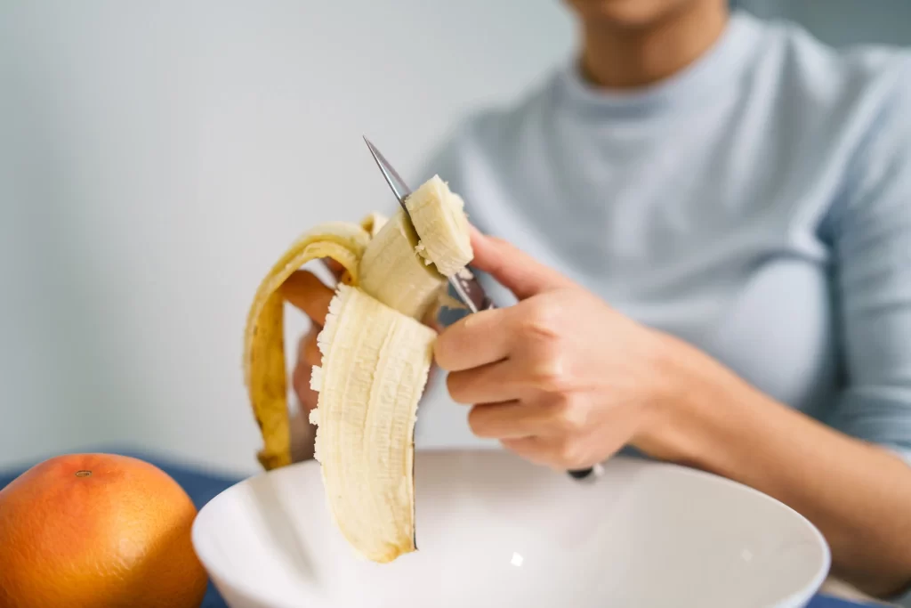 Ruka ženy krájející banány.