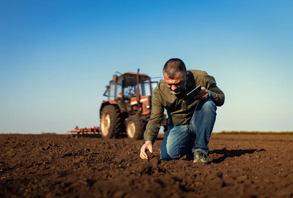 Zemědělec s traktorem na poli. 