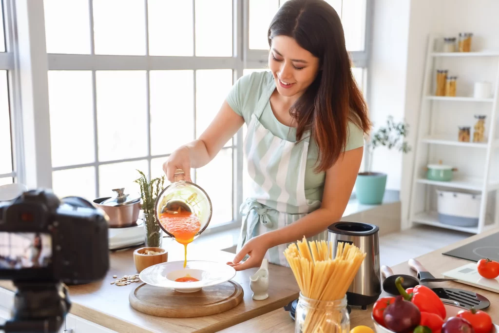Žena nalévající na talíř dýňovou polévku.