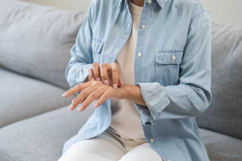 Žena drbající si komáří štípnutí na ruce.