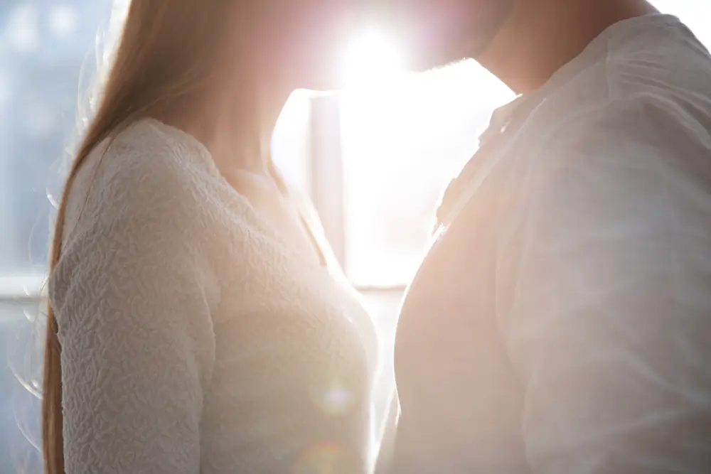 Žena a muž si d&aacute;vaj&iacute; polibek u okna. 