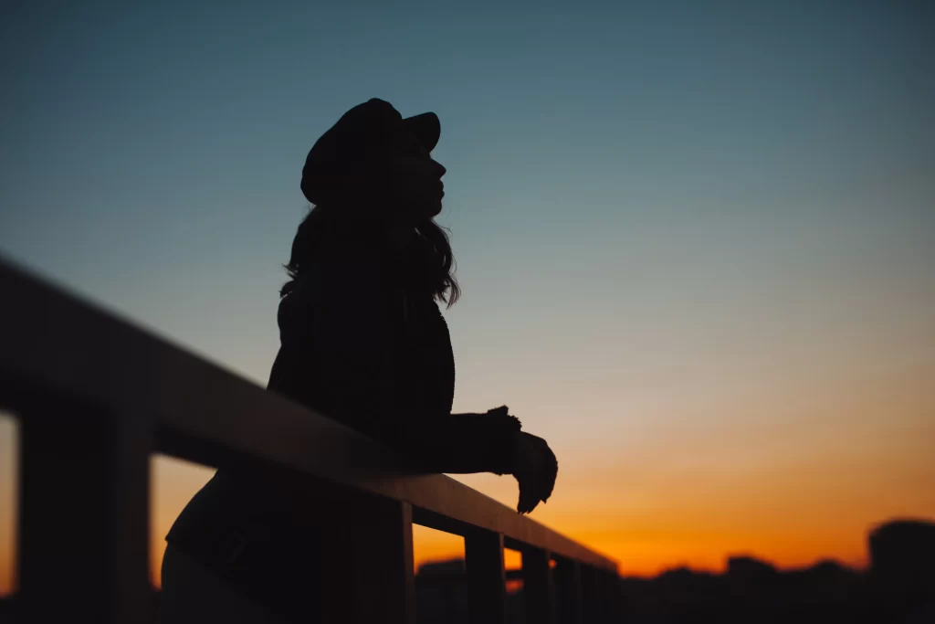 Žena d&iacute;vaj&iacute;c&iacute; se na z&aacute;pad slunce.