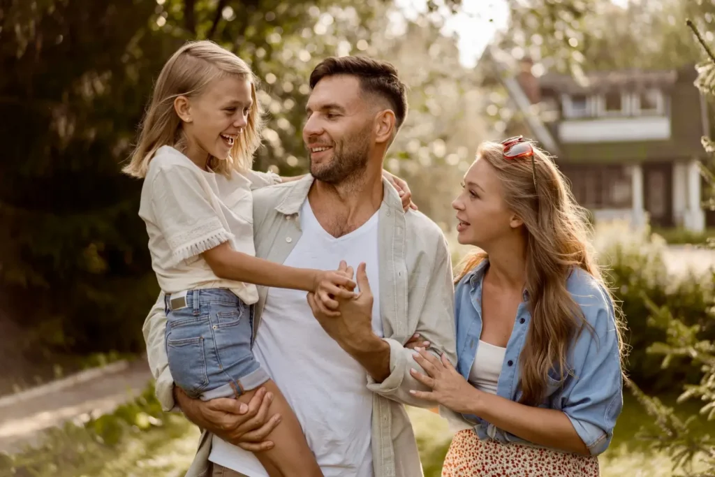 Otec drž&iacute; dceru v n&aacute;ruč&iacute; a spolu s matkou se směj&iacute; 