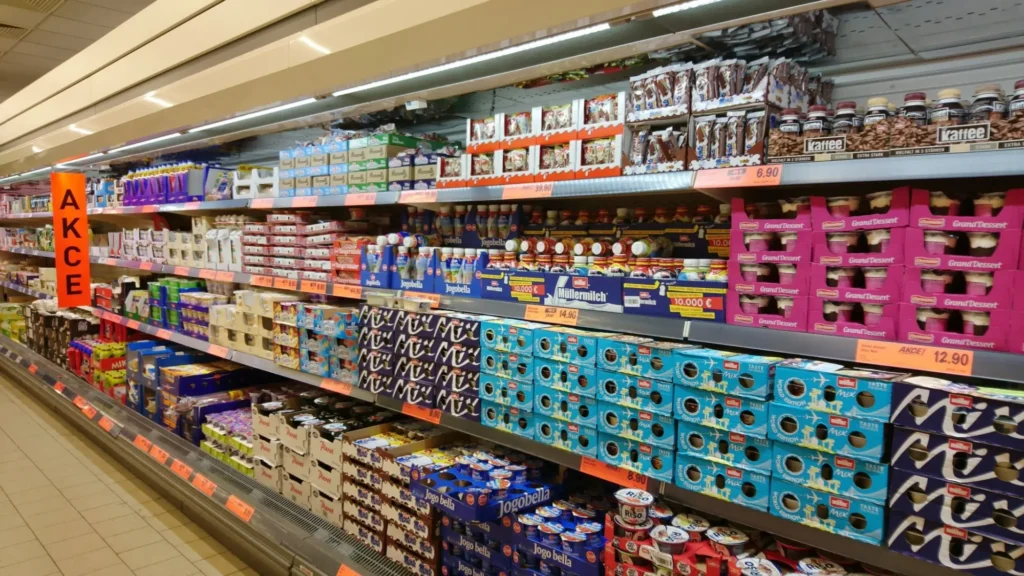 Reg&aacute;l v supermarketu pln&yacute; ml&eacute;čn&yacute;ch v&yacute;robků a dezertů, s v&yacute;razn&yacute;m oranžov&yacute;m n&aacute;pisem AKCE