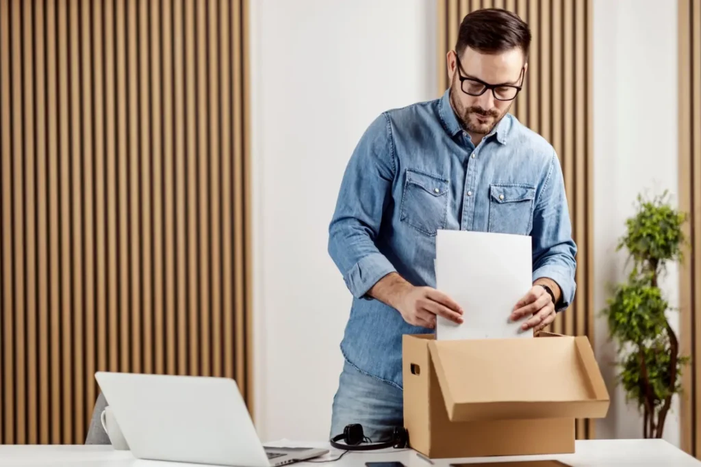 Muž tř&iacute;d&iacute; dokumenty a zakl&aacute;d&aacute; je do archivačn&iacute; krabice