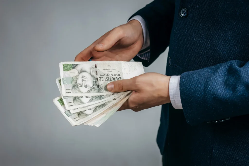 Muž drží v ruce vějíř z dvoutisícovek