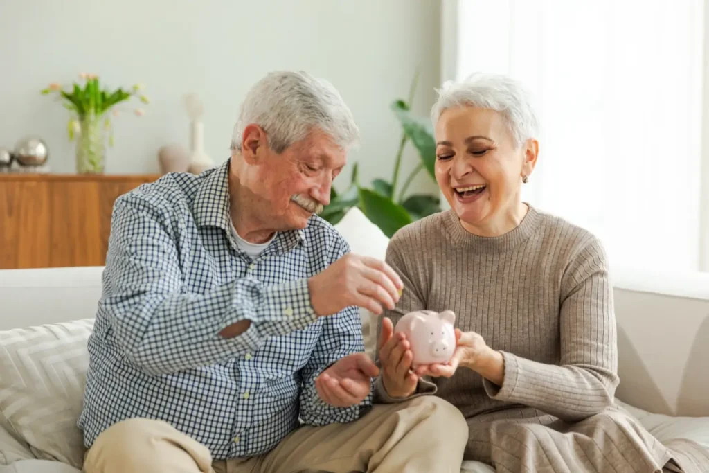 Usměvavý senior s partnerkou vkládají mince do pokladničky