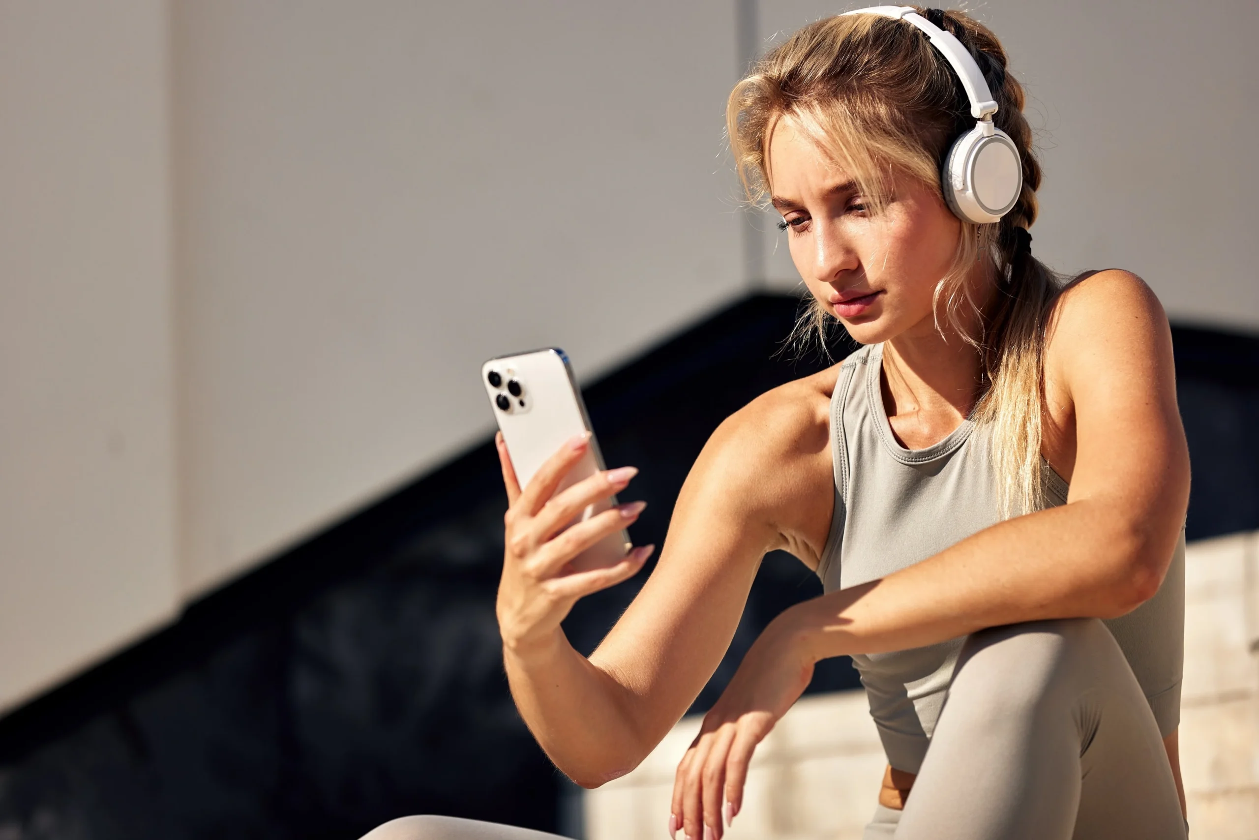 žena se sluch&aacute;tky se d&iacute;v&aacute; do mobilu