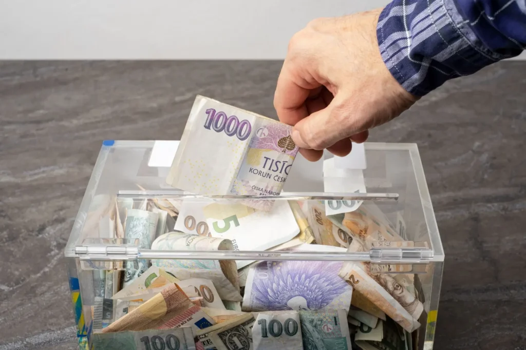 Muž strká peníze do průhledné krabice