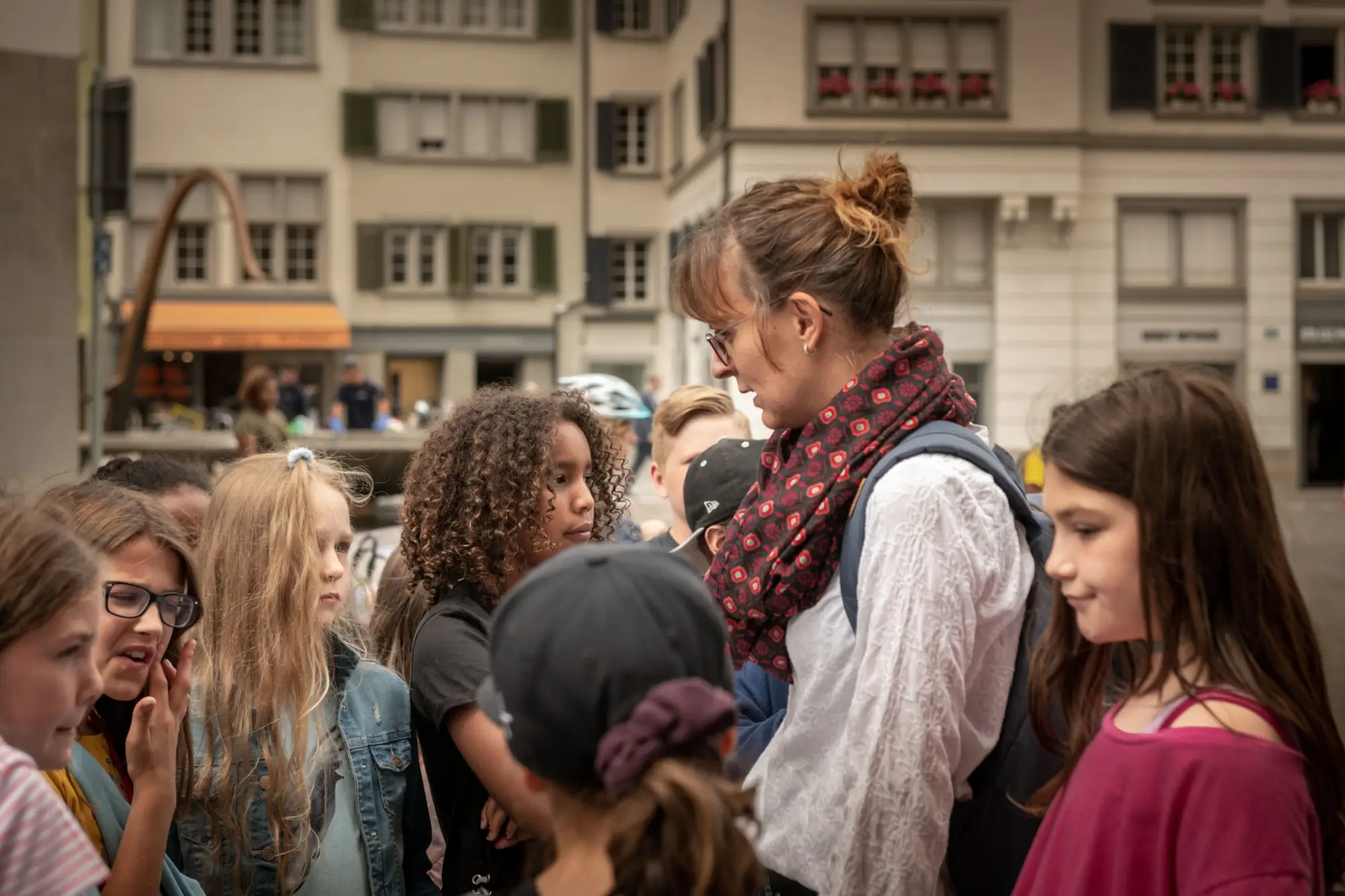 Učitelka ve Švýcarsku obklopená studenty.