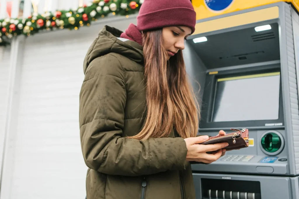 Žena se u bankomatu dívá do peněženky