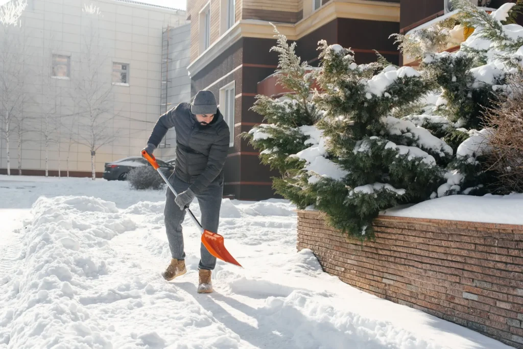 Muž odhazuje sníh před domem