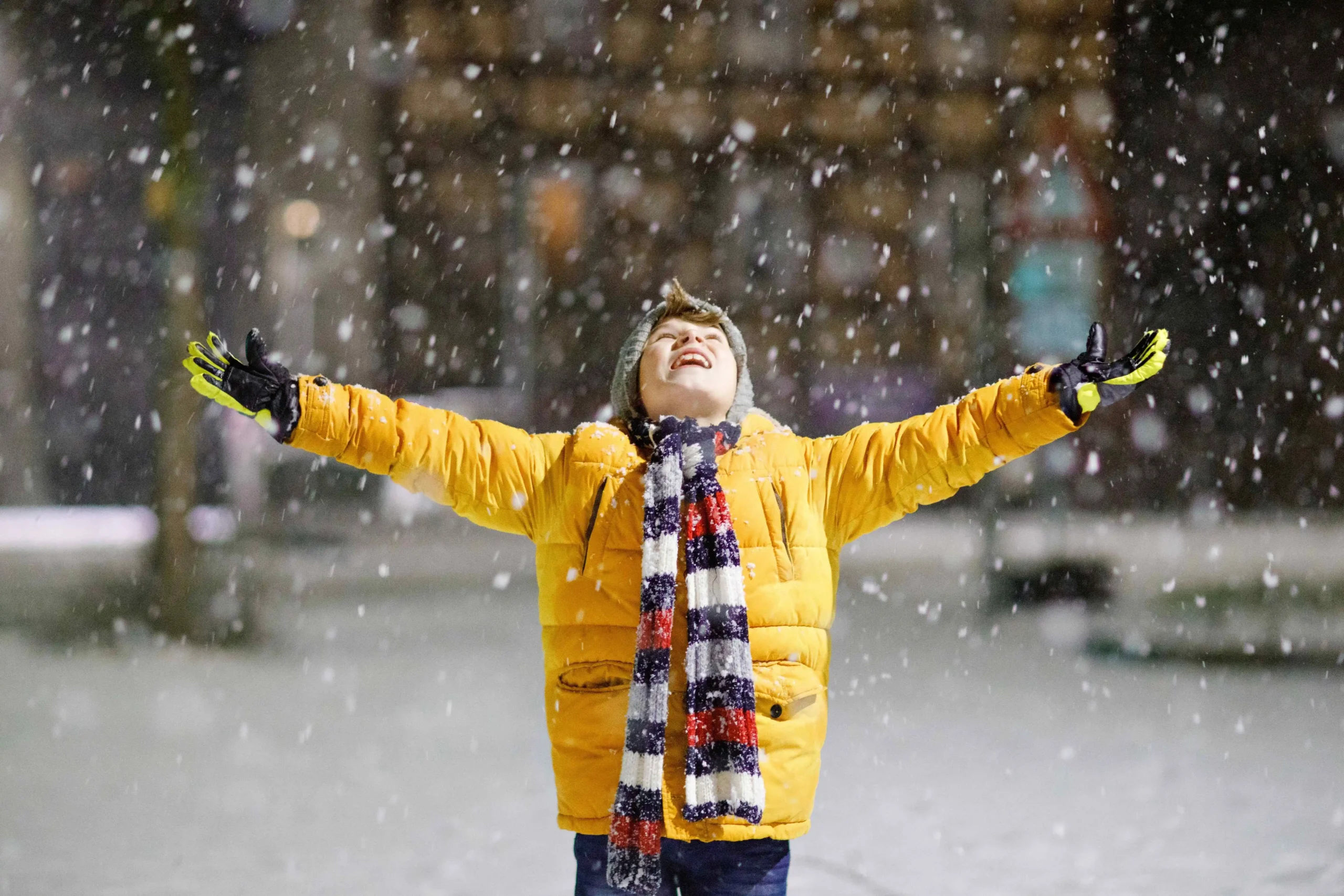 Chlapec stojí v padajícím sněhu