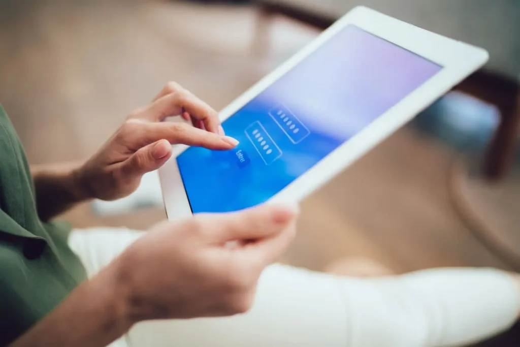 Detail rukou zadávajících heslo na tabletu s modrou přihlašovací obrazovkou