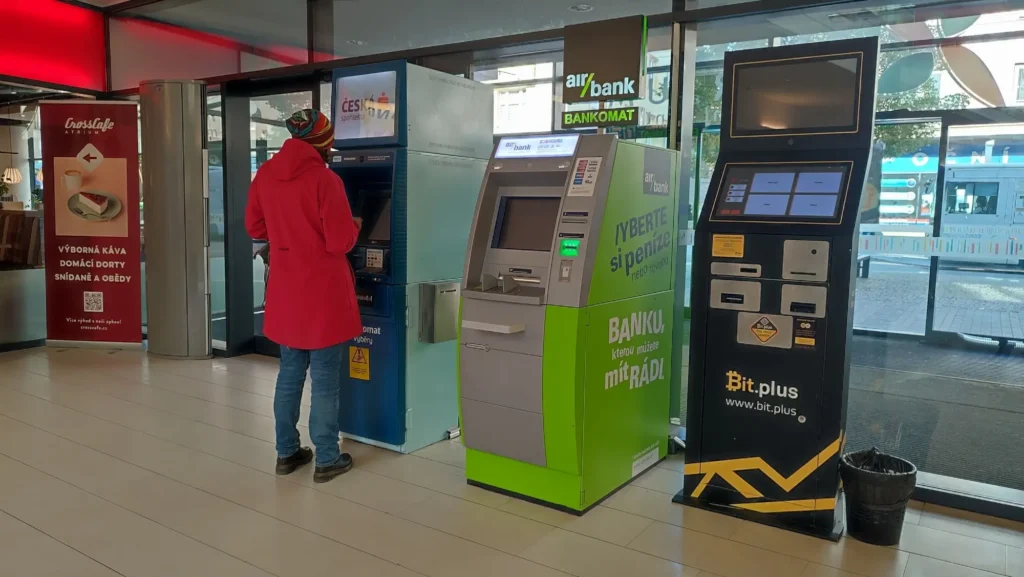 Žena v červeném vybírá peníze z bankomatu