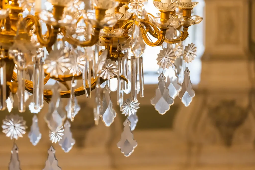 Detail zlaceného křišťálového lustru s bohatými výbrusy a broušenými kapkami