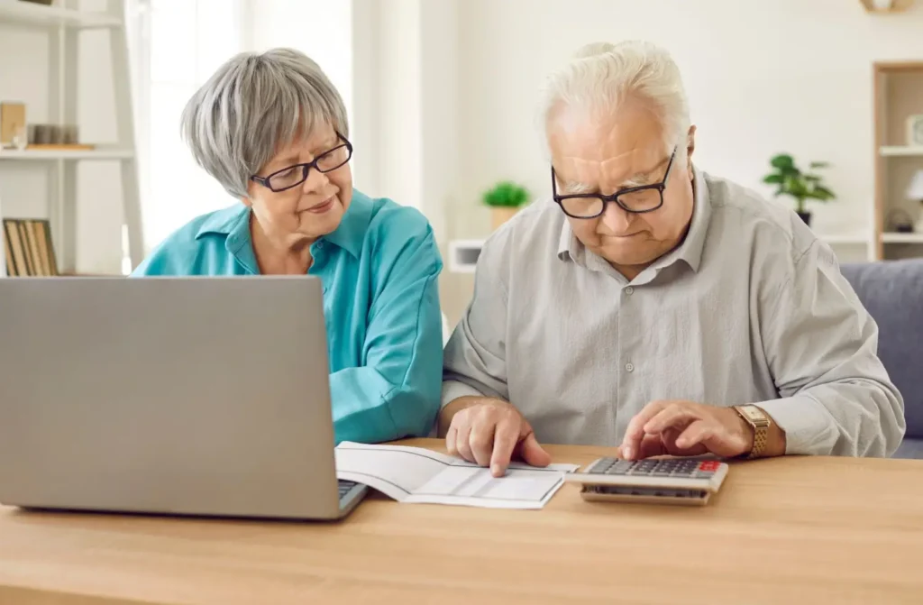Star&scaron;&iacute; muž poč&iacute;t&aacute; s kalkulačkou a žena sleduje rozpočet na pap&iacute;ře