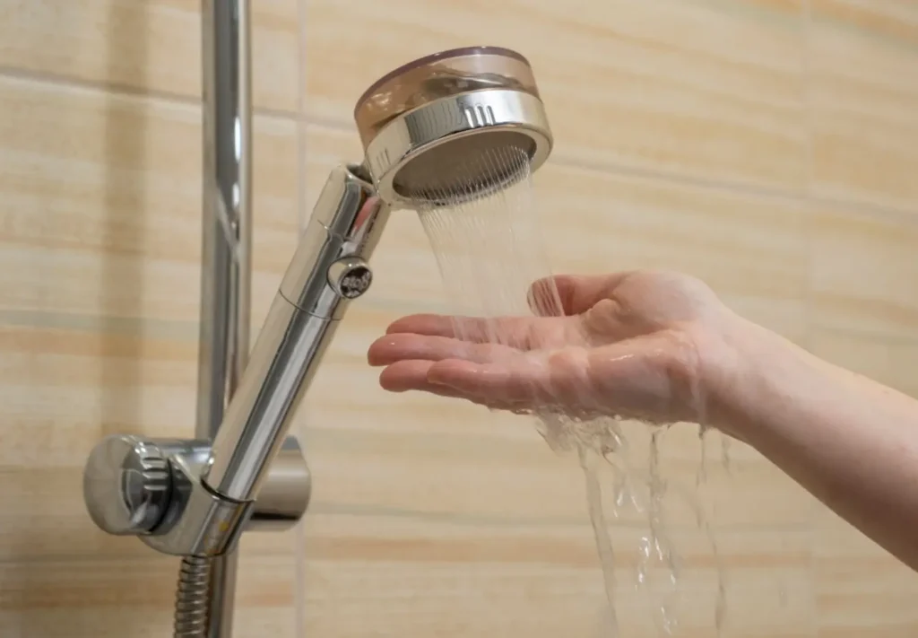 Ruka pod tekouc&iacute; vodou ze sprchov&eacute; hlavice