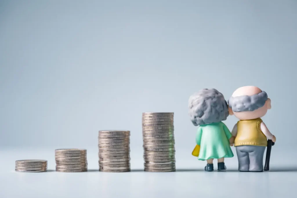 Dvě postavičky seniorů stoj&iacute; vedle rostouc&iacute;ch sloupců minc&iacute;