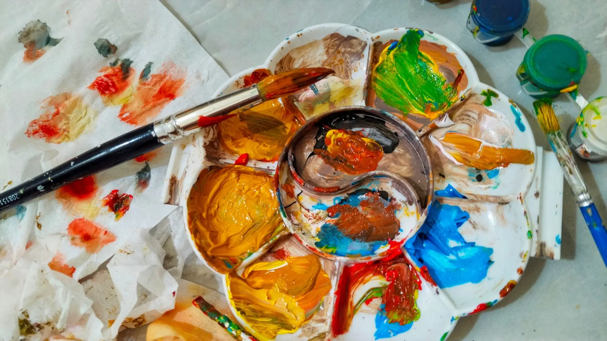 Malířská paleta s barvami u rozmalovaného díla.